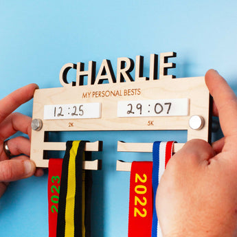 Personalised Wooden medal hanger displaying personal best times for two events.