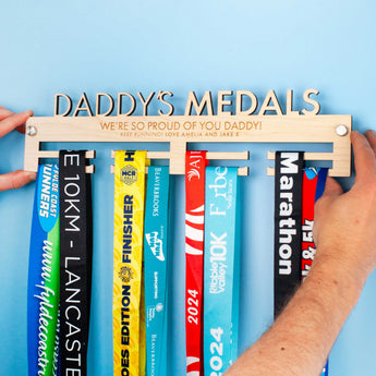 Laser engraved and laser cut Medal hanger with various medals, featuring the text 'DADDY'S MEDALS' and 'WE'RE SO PROUD OF YOU DADDY!'.