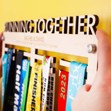 Wooden medal holder with 'Running Together' text, personalised with two lines of custom text with brushed aluminium wall mount fixings