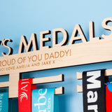 Detailed view of the message laser engraved on a Wooden medal hanger personalised with 'Daddy's Medals'.