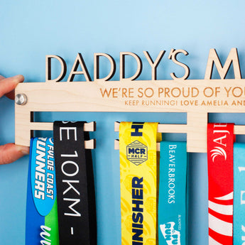 Wooden medal hanger personalised with 'Daddy's Medals', with the included Brushed Aluminium Wall Fixing Mounts shown.