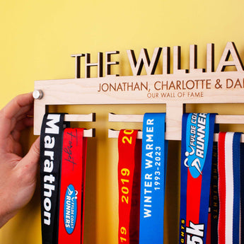 Personalised Wooden Family Medal Hanger, featuring the surname and all the family's first names showcasing the included brushed aluminium wall mount fixings