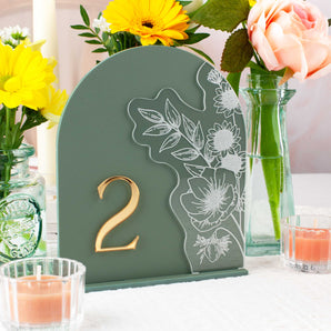 Decorative table number with floral design on a table with flowers and candles