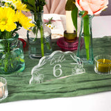 Decorative table setting with flowers, candles, and a table number card on a green tablecloth.